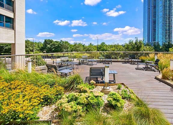 A rooftop garden with a table and chairs overlooking a city skyline.