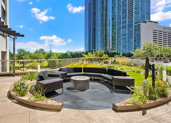 A modern outdoor seating area with a circular table surrounded by chairs and plants.