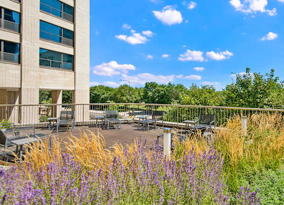 A building with a patio surrounded by purple flowers.