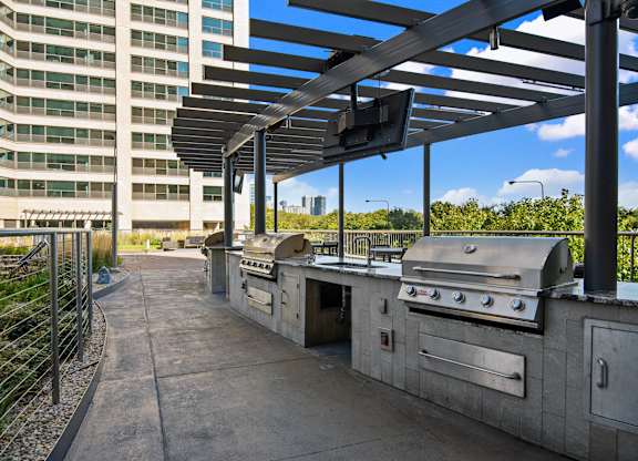 A patio with a grill and a building in the background.