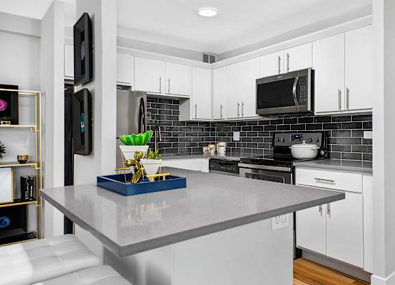A modern kitchen with a grey countertop and white cabinets.
