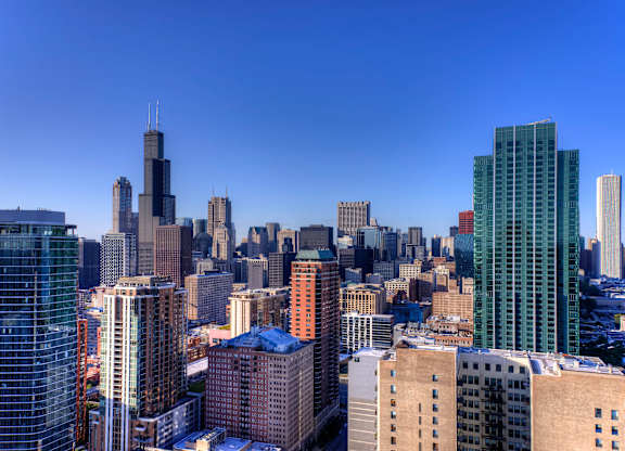 A cityscape with a mix of modern and older buildings under a clear blue sky.