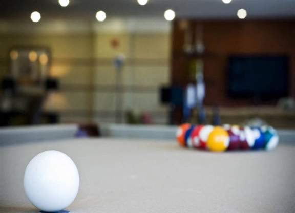 A white ball is on a pool table.