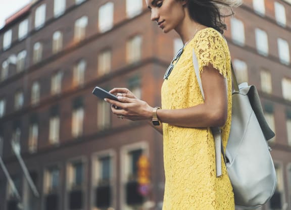 a woman in a yellow dress looking at her cell phone