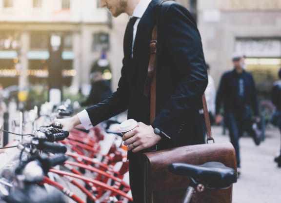 a man in a suit standing next to a row of bikes