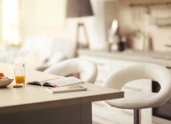 a kitchen table with a book and a glass of juice on it