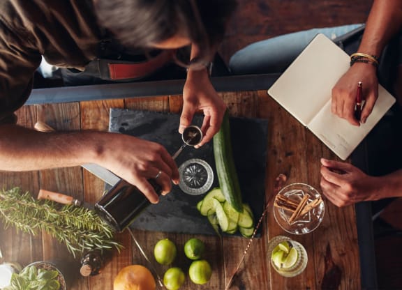 a person pouring wine into a bottle on a table with fruits and vegetables