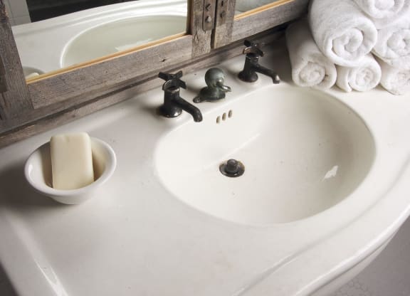 a bathroom sink with a bowl of soap and towels