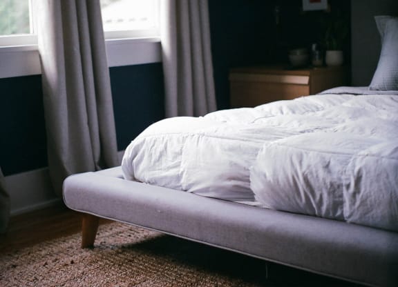 a bed with a white comforter and pillows in a bedroom