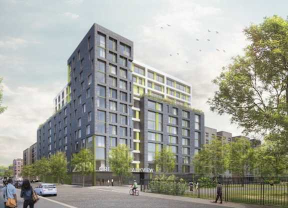 A modern building with a glass facade is surrounded by trees and people are walking around.