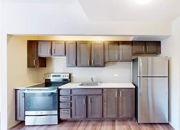 A kitchen with a stainless steel refrigerator, oven, and sink.