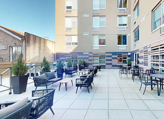 A patio with chairs and tables is surrounded by buildings.
