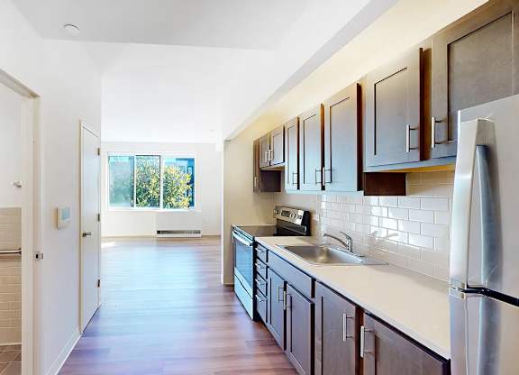 A kitchen with wooden cabinets and a stainless steel refrigerator.