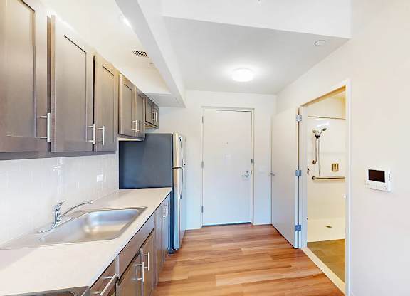 A kitchen with a black fridge and wooden floors.