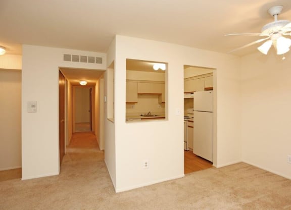 an empty living room and kitchen with a ceiling fan