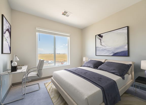 a bedroom with a large window and a desk with a chair