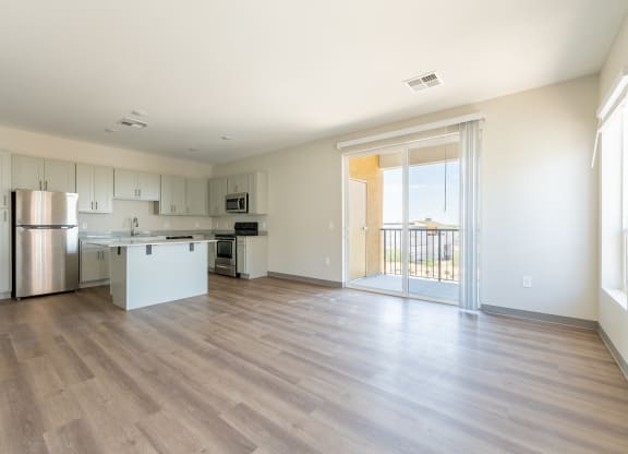 a kitchen and living room with a sliding glass door leading to a balcony