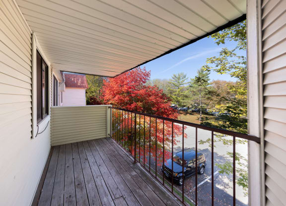 A balcony with a wooden floor and a metal railing at Heritage Hills Apartments, Bloomington, 55437
