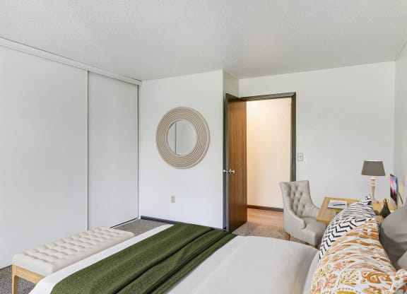 a bedroom with a bed and a chair and a door to a closet