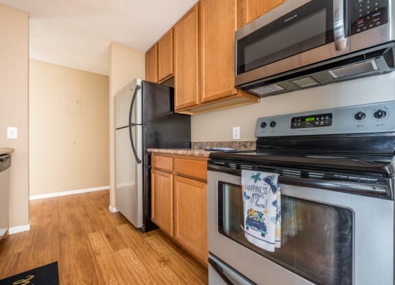 a kitchen with wood cabinets and stainless steel appliances at Heritage Hills Apartments, Bloomington