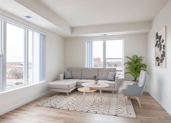 a living room with a gray couch and a rug and large windows