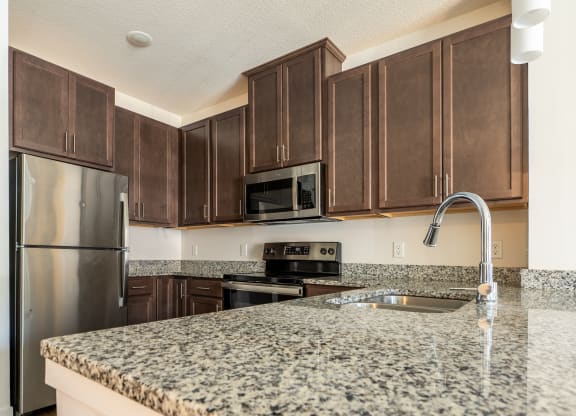 a kitchen with granite countertops and dark wood cabinets