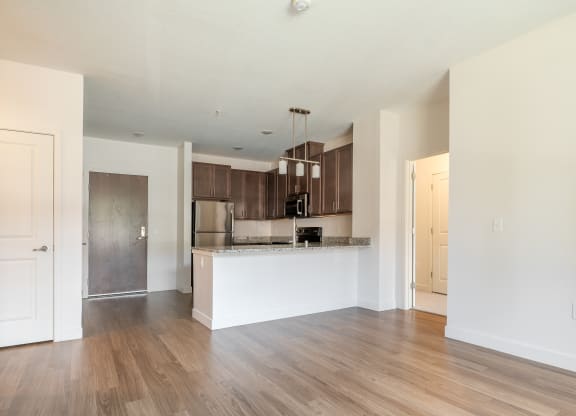 a kitchen and living room with hardwood floors and white walls