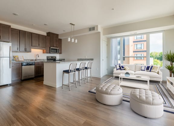 a living room and kitchen with wood flooring and a large window