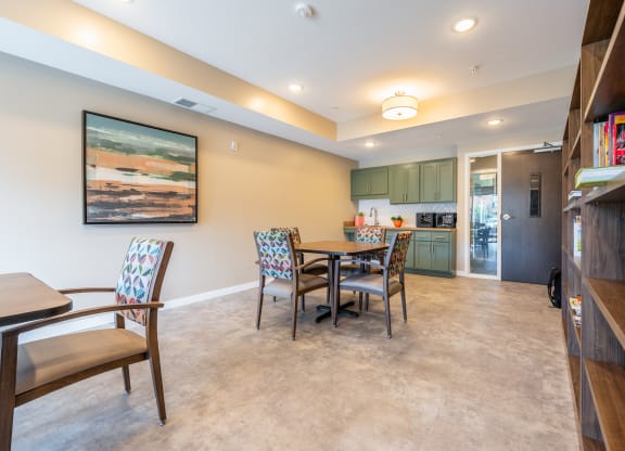 a dining area with a table and chairs and a kitchen in the background