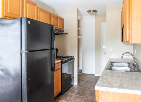 a kitchen with black appliances and wooden cabinets at Northtown Village Apartments, Spring Lake Park, 55432-2650