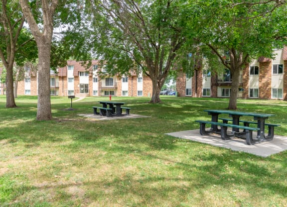 two picnic tables in a grassy area in front of a brick building at Northtown Village Apartments, Spring Lake Park, MN