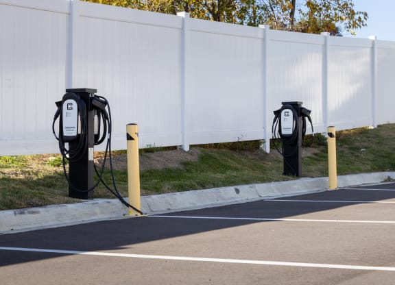 a row of electric parking meters in front of a white fence