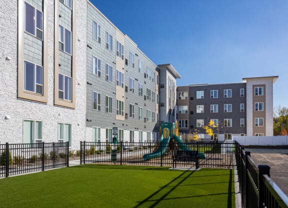 a playground in front of an apartment building with a play set