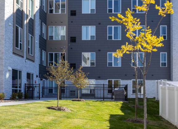 a courtyard with grass and trees in front of an apartment building