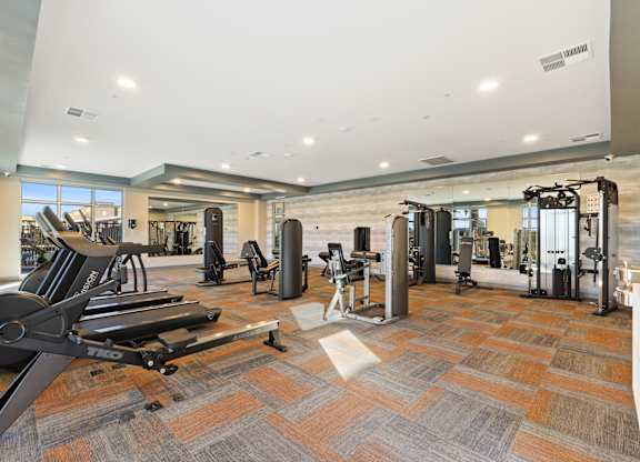 A gym with a variety of equipment including treadmills, weights, and exercise machines at Agave House Apartments, Arizona