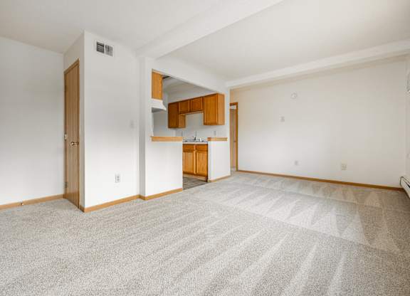 an empty living room and kitchen with white walls and carpet at Ames Lake Neighborhood Apartments, Minnesota