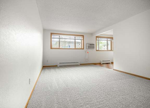 the living room and dining room of a house with white walls and a carpet at Ames Lake Neighborhood Apartments, St. Paul
