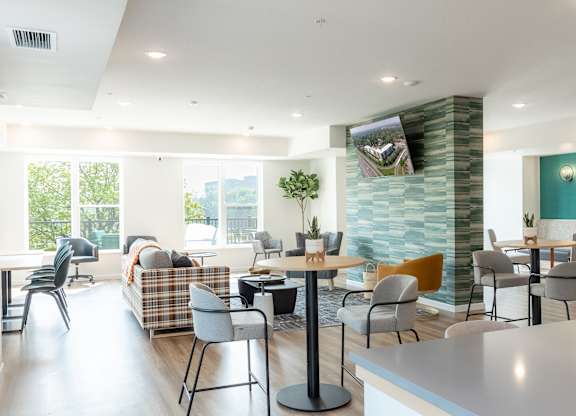 A modern living room with a large window, a couch, a coffee table, and a TV mounted on the wall.