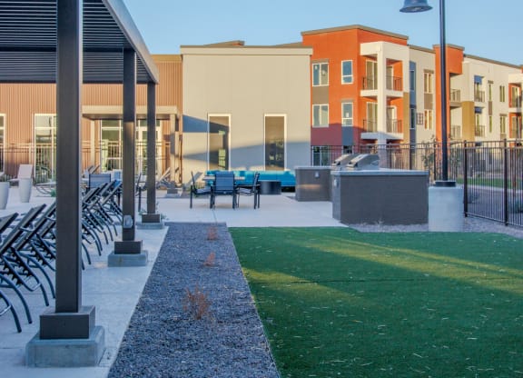a grassy area with benches and a pool in front of a building