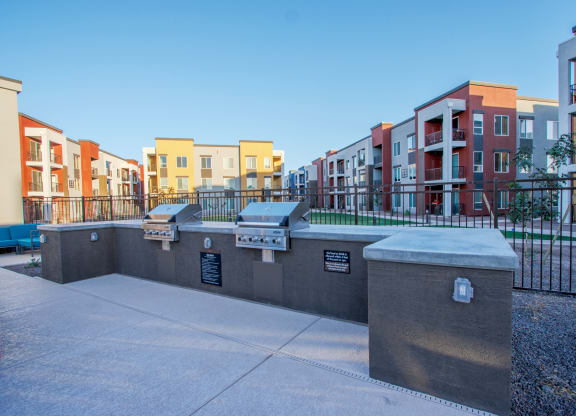 an open area with benches and a fence with apartments in the background