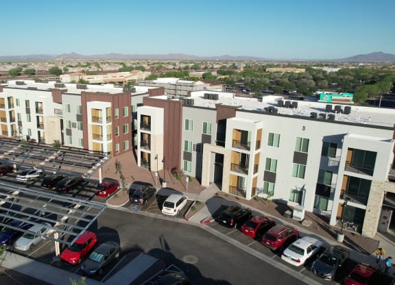 an aerial view of a large apartment complex with a parking lot and cars in the lot