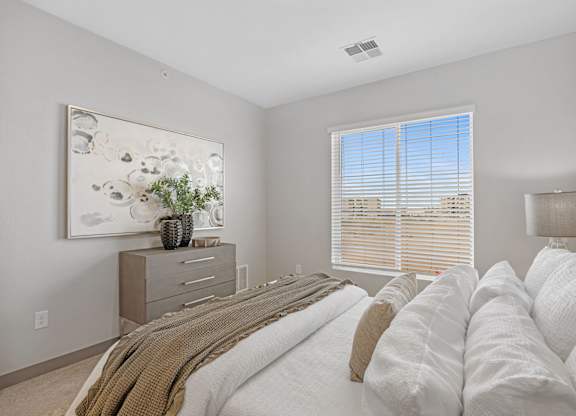 A bedroom with a large bed and a painting on the wall at Copa Flats Apartments, Maricopa