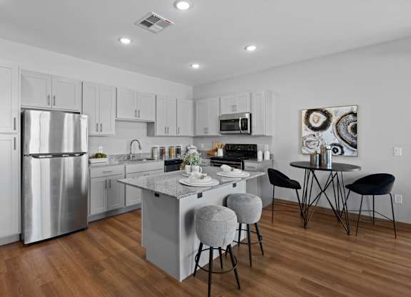 A modern kitchen with a large island and stools at Copa Flats Apartments, Maricopa, Arizona