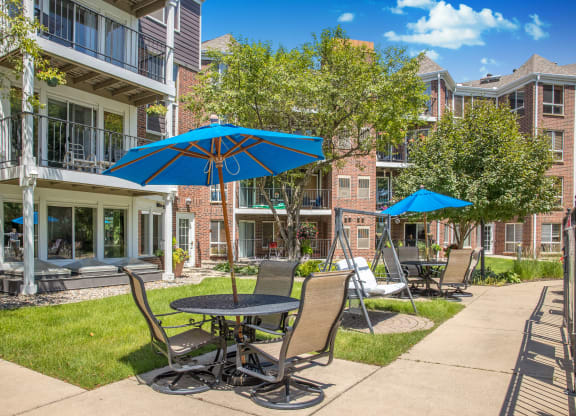 a patio with tables and chairs and umbrellas in front of an apartment building
