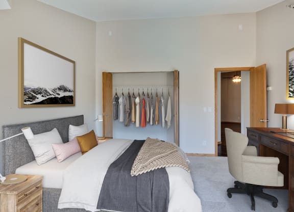 a bedroom with a bed and a closet with clothes on it