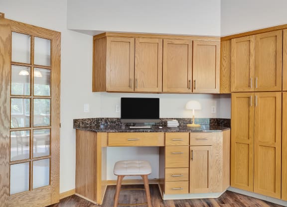 a home office with wooden cabinets and a desk with a computer