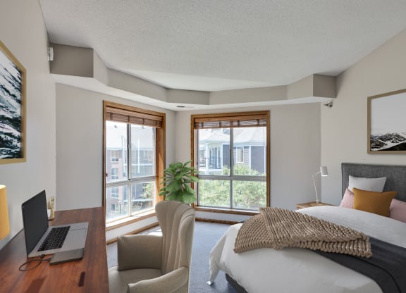 a bedroom with a bed and a laptop on a desk