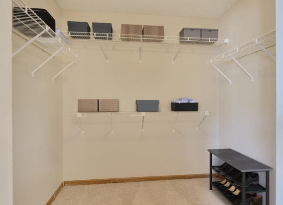 a walk in closet with shelves and a rack on the wall