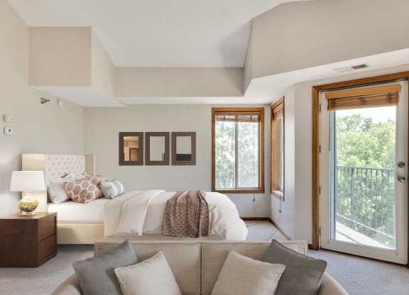 a bedroom with a bed and a couch and a door to a balcony