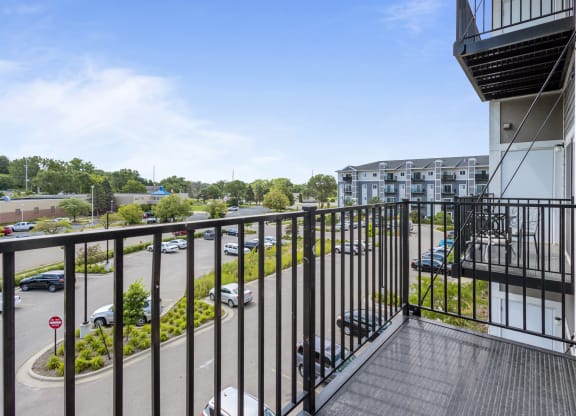 a balcony with a view of a parking lot and a building at EastGate Apartments, Rochester